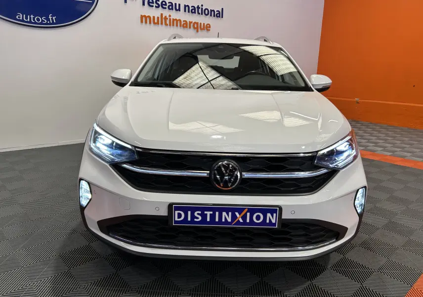 Vue frontale d'un Volkswagen Taigo blanc pur 2022 avec phares LED allumés et calandre noire brillante.