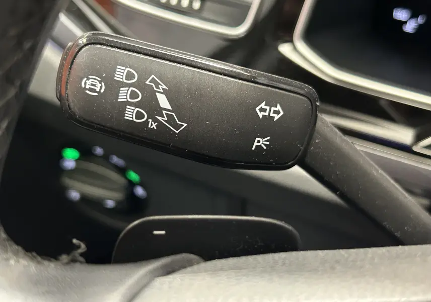 Gros plan sur la commande de clignotants noire du Volkswagen Taigo blanc, avec pictogrammes blancs visibles.