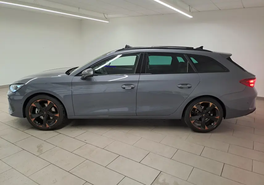 Vue de profil côté gauche d'une CUPRA Leon ST 2025 gris Graphène avec jantes cuivrées et toit ouvrant panoramique.