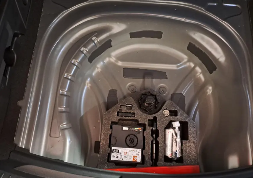 Vue plongeante sur le coffre ouvert d'une CUPRA LEON ST 2025, montrant la roue de secours et les outils intégrés.
