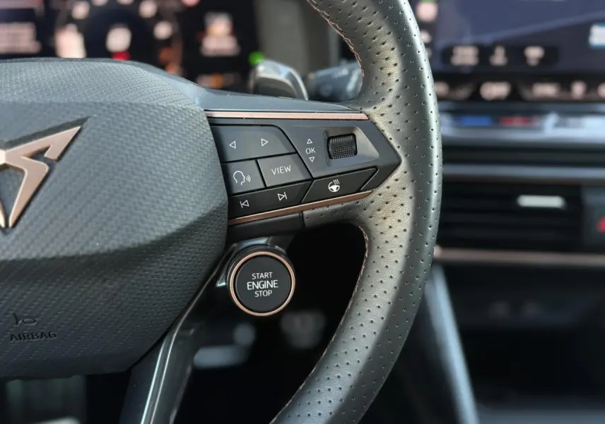 Gros plan sur le volant cuir perforé noir de la CUPRA Leon 2025 avec boutons multifonctions et bouton start engine stop.