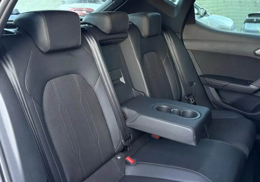 Vue intérieure côté droit des sièges arrière noirs bimatière avec accoudoir central et porte-gobelets du CUPRA Leon 2025.