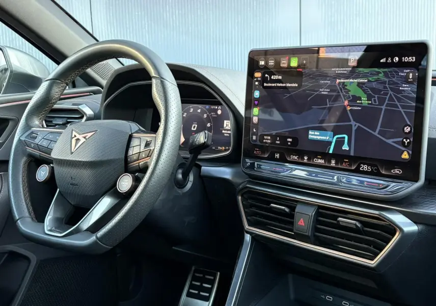 Vue intérieure centrée sur le volant cuir perforé et l'écran tactile HD 12,9'' du tableau de bord de la CUPRA Leon 2025.
