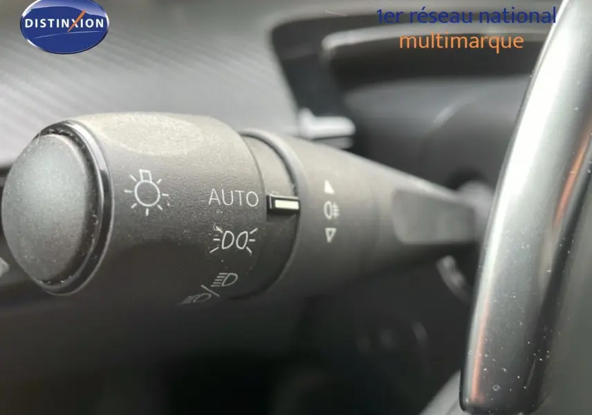 Gros plan sur la commande des phares à gauche du volant dans l’habitacle noir d’une Peugeot 508 SW noire.