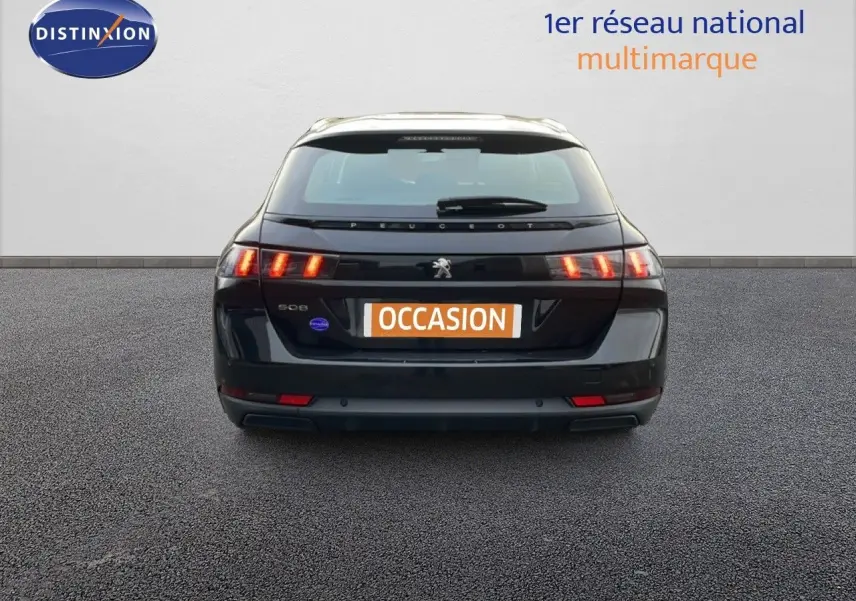 Vue arrière d'une Peugeot 508 SW noire Perla Nera Metal avec feux arrière allumés sur fond neutre.