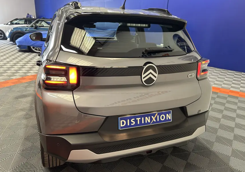Vue arrière d'une Citroën C3 Turbo 100 PLUS gris Artense avec feux LED allumés dans un showroom.