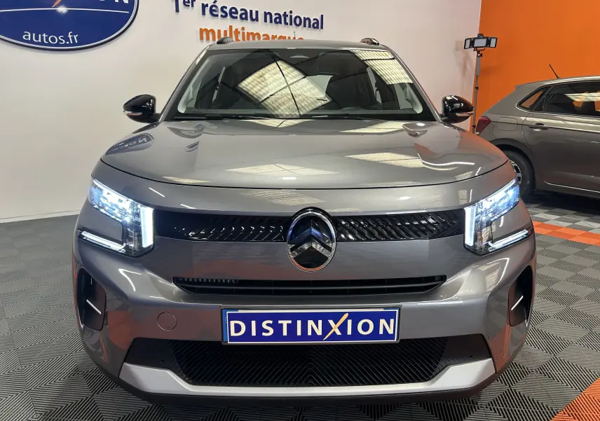 Vue frontale d'une Citroën C3 Turbo 100 PLUS gris Artense avec phares LED allumés dans un showroom.