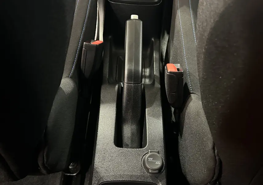 Vue rapprochée de la console centrale intérieure de la Citroën C3 Turbo 100 PLUS, montrant frein à main et prises 12V.