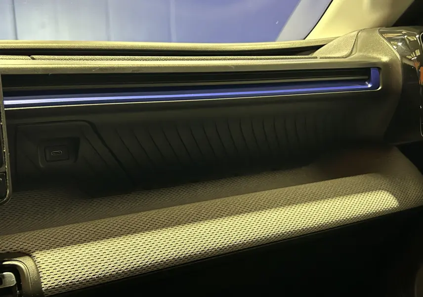 Détail de la planche de bord intérieure de la Citroën C3 2025 avec bandeau lumineux bleu et finition tissu gris clair.