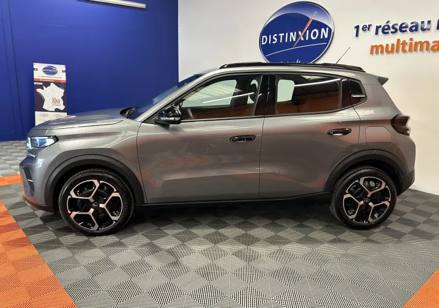 Vue de profil côté gauche d'une Citroën C3 2025 gris Artense avec jantes bi-ton et toit noir en showroom.