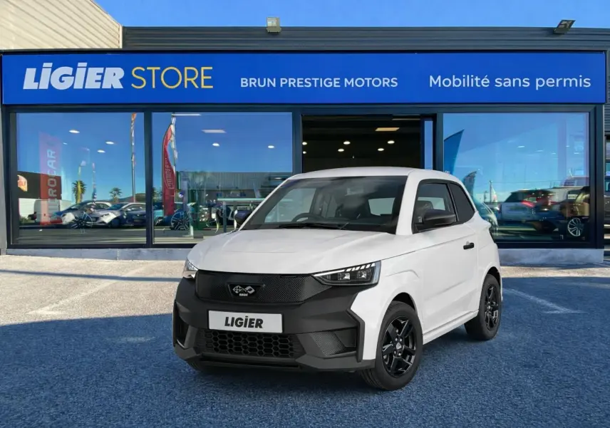 Vue 3/4 avant d'une Ligier JS50 Select Revo D+ blanc glacier avec calandre noire et jantes noires devant un showroom.