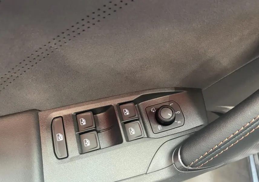 Détail des commandes de lève-vitres et réglage des rétroviseurs côté conducteur d’une CUPRA Leon gris intérieur suédine.