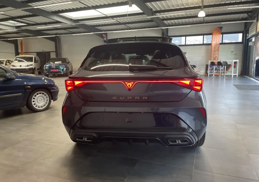 Vue arrière d'une CUPRA Leon gris magnétique avec feux arrière en bandeau lumineux Tri-LED et double sortie d'échappement noire.