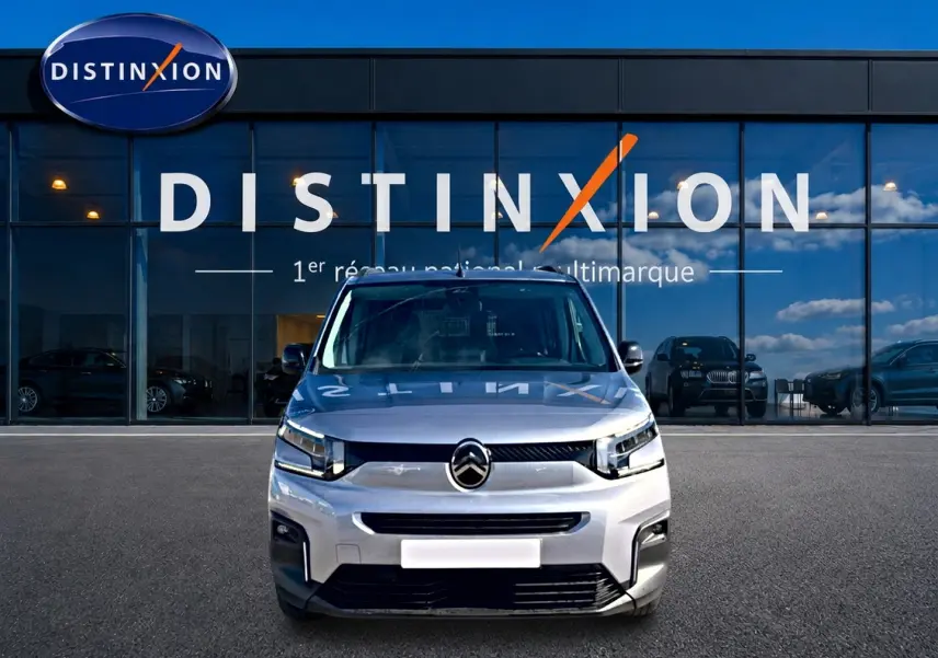 Vue frontale d'un Citroën Berlingo 2026 gris acier, avec calandre distinctive et phares LED devant un showroom Distinxion.