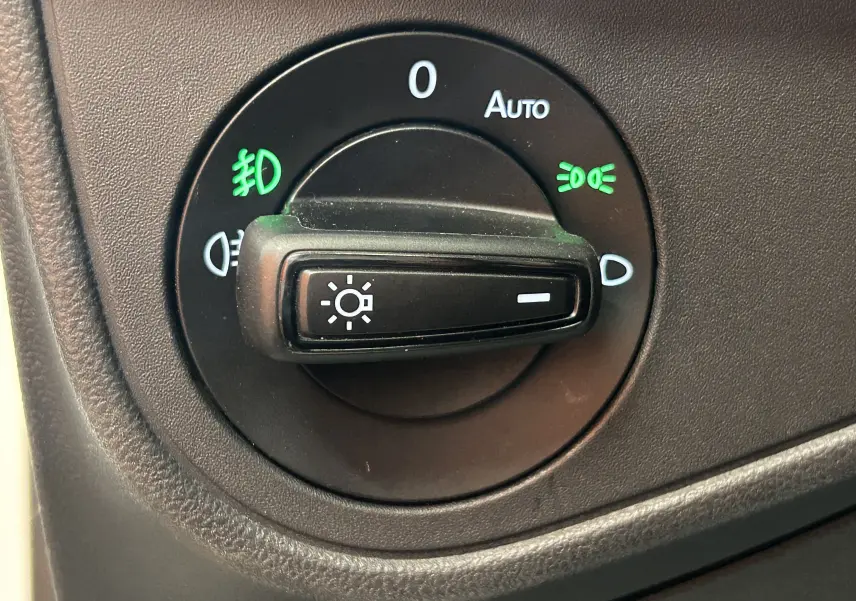 Gros plan sur le sélecteur de phares noir du Volkswagen Taigo TSI 110 DSG7 Style 2022, avec symboles verts allumés.