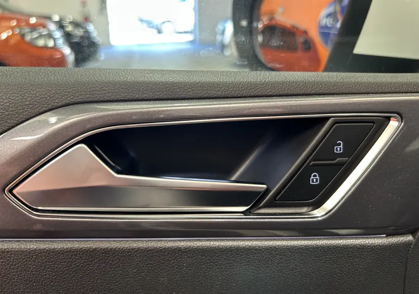 Poignée intérieure de porte côté gauche du Volkswagen Taigo blanc, avec boutons de verrouillage éclairés.