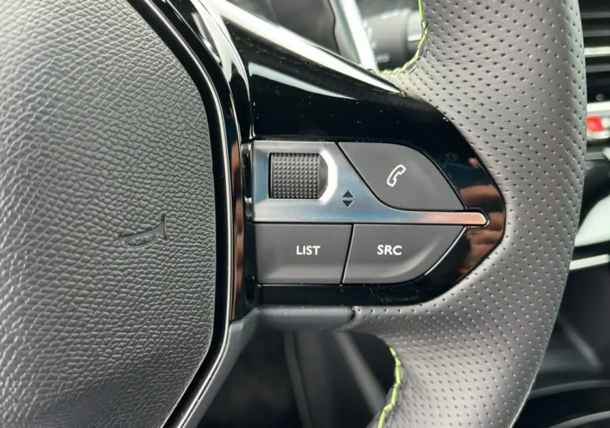 Gros plan sur les commandes gauche du volant perforé du Peugeot 2008 Hybrid 145 GT Vision 2025, finition noire.