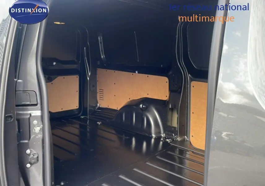 Vue intérieure du coffre arrière ouvert du Citroën Jumpy gris titane, montrant l’espace de chargement vide et les panneaux latéraux en bois.