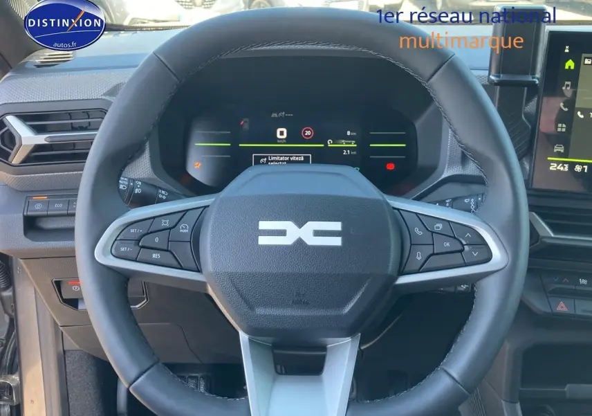 Vue rapprochée du volant multifonction noir du Dacia Duster 1.2 mild hybrid 140 Journey avec tableau de bord numérique allumé.