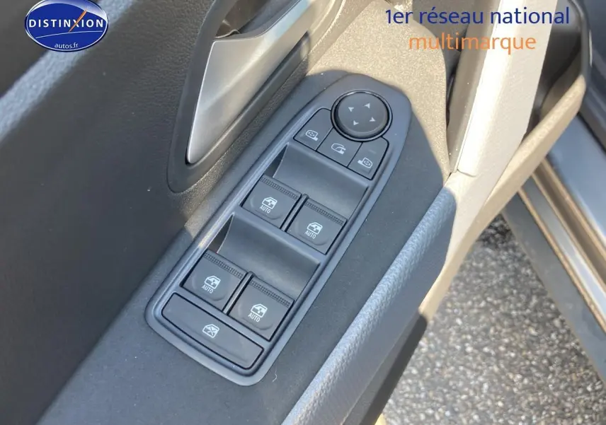 Gros plan sur la commande des vitres électriques côté gauche d’un Dacia Duster gris schiste, avec poignée argentée.