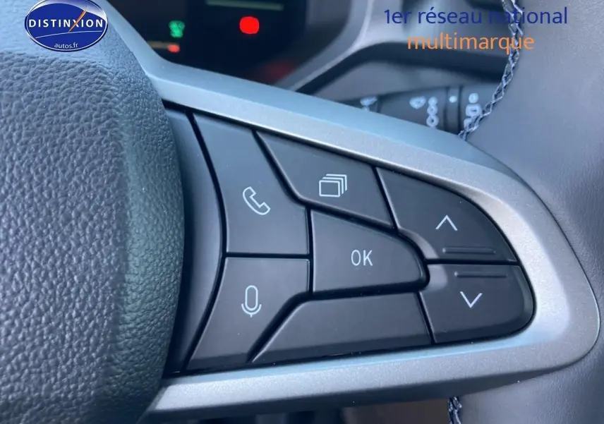 Gros plan sur les commandes multifonctions à droite du volant du Dacia Duster gris schiste, avec boutons de navigation et appel.