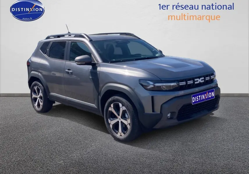 SUV Dacia Duster gris schiste en 3/4 avant droit, avec barres de toit et jantes alliage visibles.