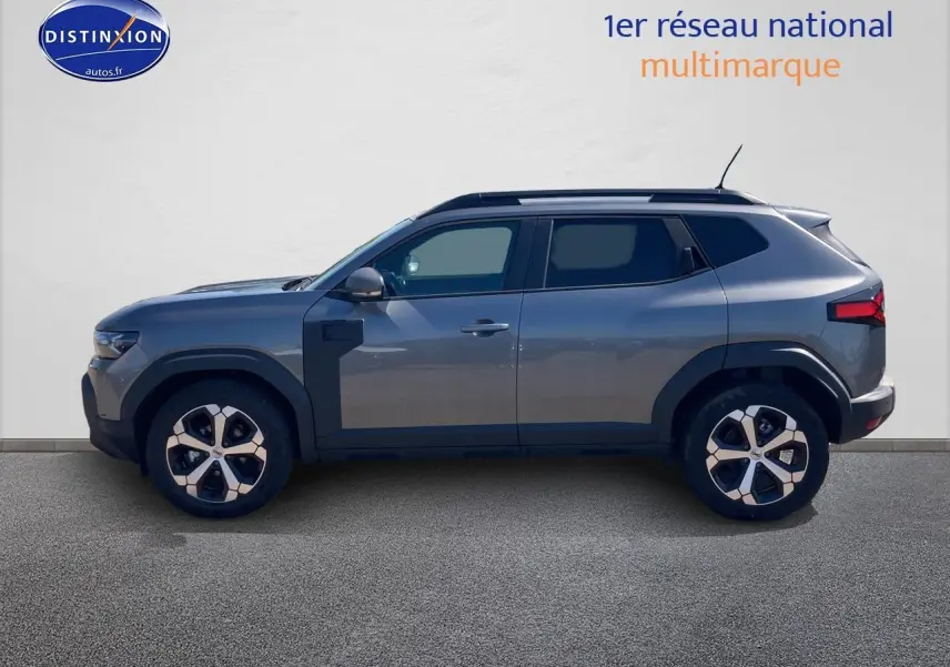 Profil droit du Dacia Duster 1.2 mild hybrid 140 Journey gris schiste avec jantes alu et barres de toit visibles.