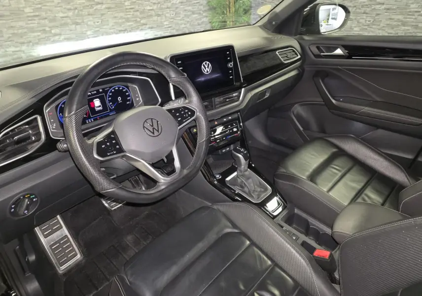 Vue intérieure côté conducteur du Volkswagen T-Roc 2023 noir, avec sellerie cuir Nappa et tableau de bord Piano Noir.