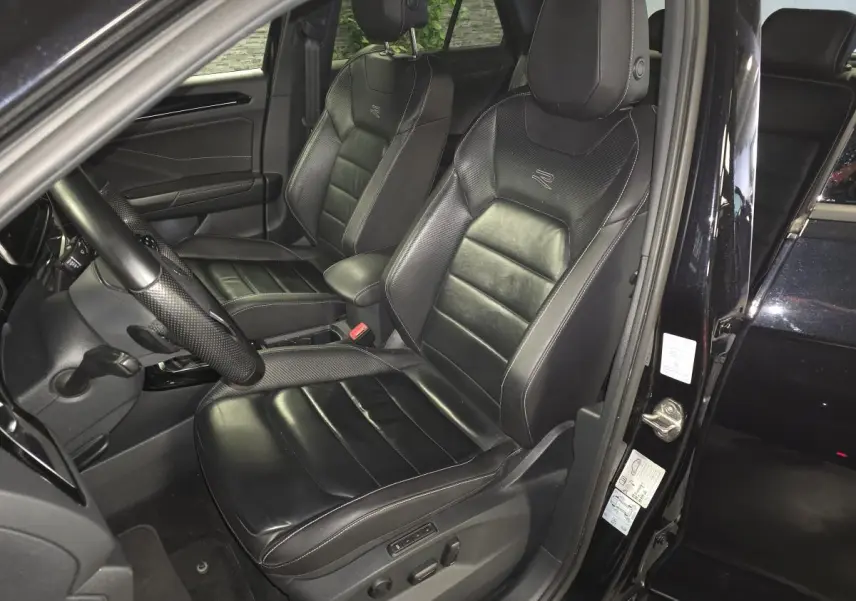 Vue intérieure côté conducteur du Volkswagen T-Roc noir 2023, sièges cuir Nappa R-Line avec réglages électriques et logo R-Line.