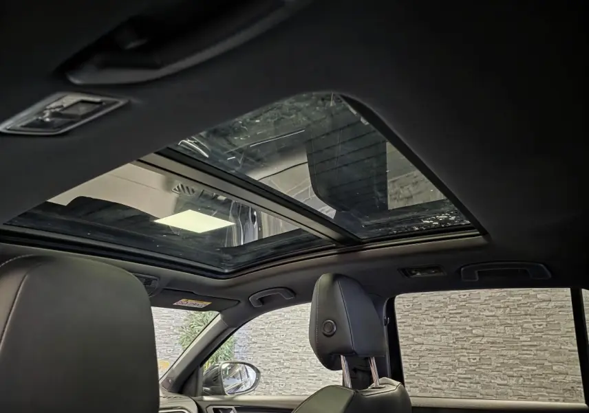 Vue intérieure du toit ouvrant panoramique en verre du Volkswagen T-Roc noir avec sièges avant en cuir noir.