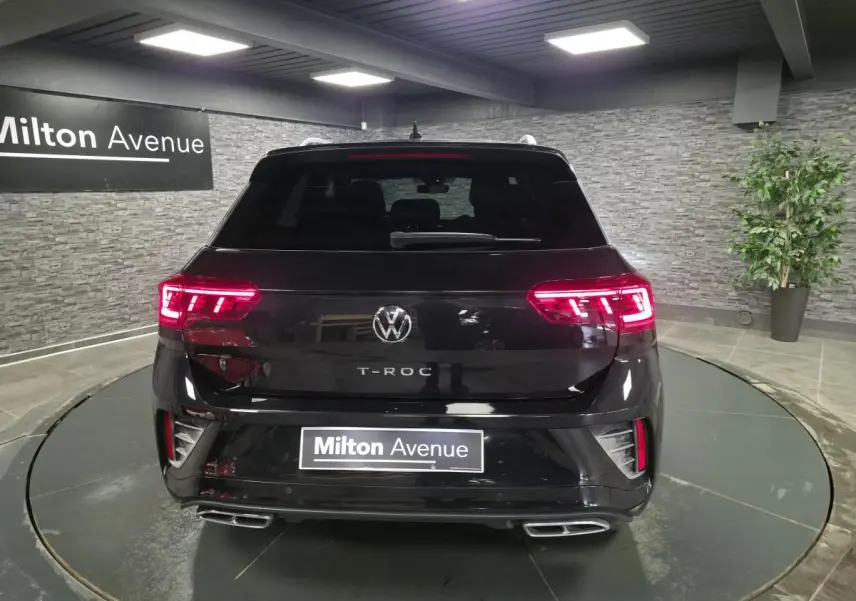 Vue arrière d'un Volkswagen T-Roc noir 2023 avec feux LED allumés et double sortie d'échappement rectangulaire.
