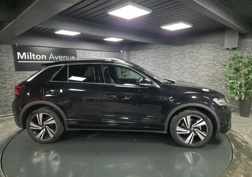 Volkswagen T-Roc noir vue de profil côté gauche, avec jantes alliage distinctives et toit ouvrant en verre.