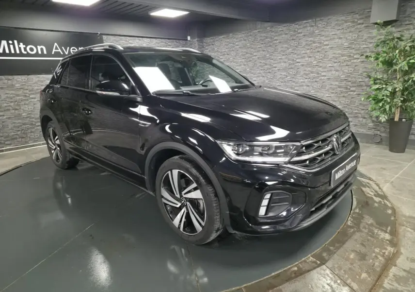 Volkswagen T-Roc noir en 3/4 avant droit, avec jantes alliage et calandre R-Line visible en showroom.