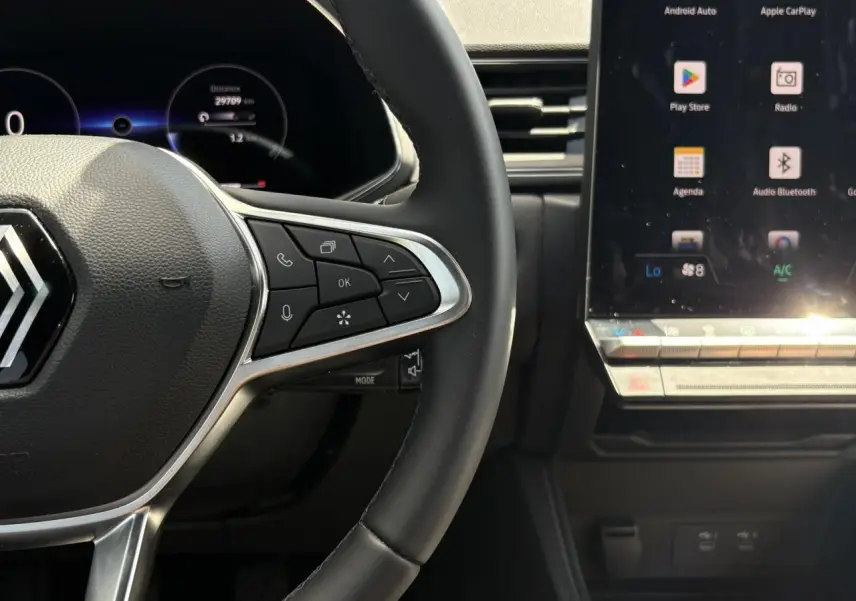 Gros plan sur le volant noir et les commandes multifonctions à droite, avec écran tactile du tableau de bord du Renault Captur TCE 90.