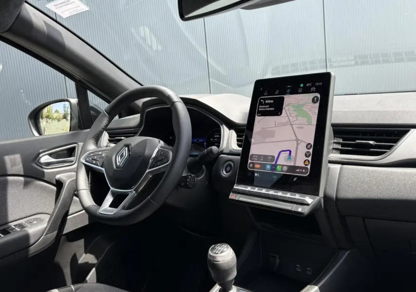 Vue intérieure côté conducteur du Renault Captur TCE 90 Techno 2025, avec tableau de bord numérique et écran GPS vertical.