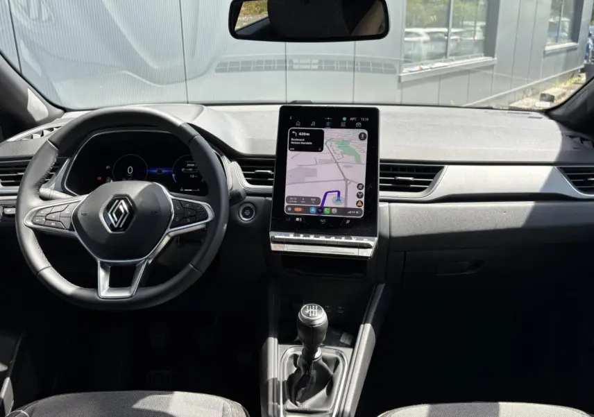 Vue intérieure avant du Renault Captur TCE 90 Techno 2025, tableau de bord avec écran GPS vertical et volant multifonction.