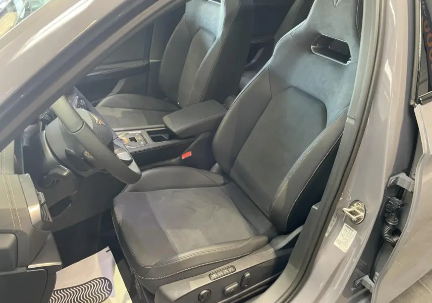 Vue intérieure côté conducteur de la CUPRA Leon 2026 gris, sièges baquets suédine noire avec surpiqûres cuivrées et logo Cupra.