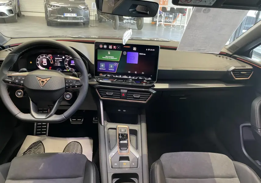 Vue intérieure avant de la CUPRA Leon 2026, tableau de bord noir avec écran tactile central et volant sport marqué Cupra.