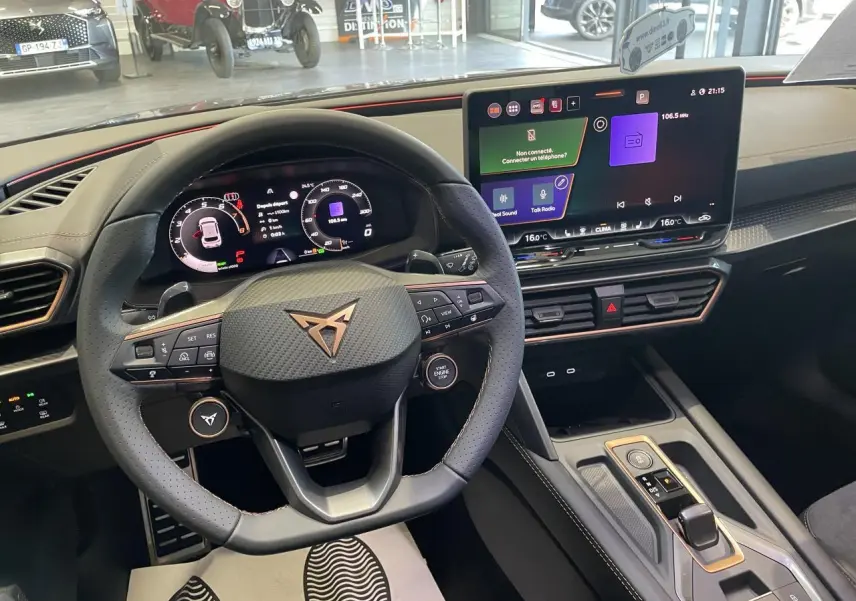 Vue intérieure du poste de conduite de la CUPRA Leon gris, avec volant sport et écran tactile HD 12,9 pouces.