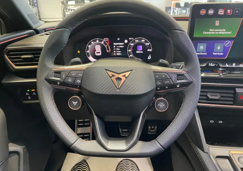 Volant perforé gris avec logo Cupra cuivré, tableau de bord digital et écran tactile dans l'habitacle du Cupra Leon 2026.