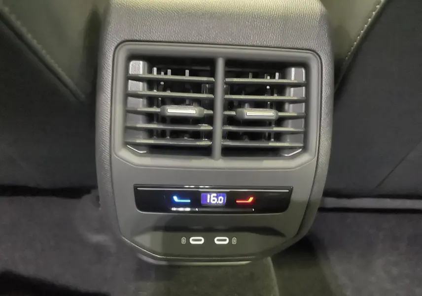 Gros plan sur la console arrière de la CUPRA Leon gris, avec bouches d’aération et commandes climatisation à 16°C.