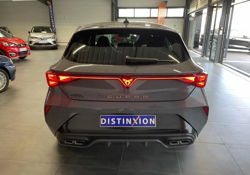 Vue arrière d'une CUPRA Leon gris magnétique avec bandeau lumineux et double sortie d'échappement stylisée.