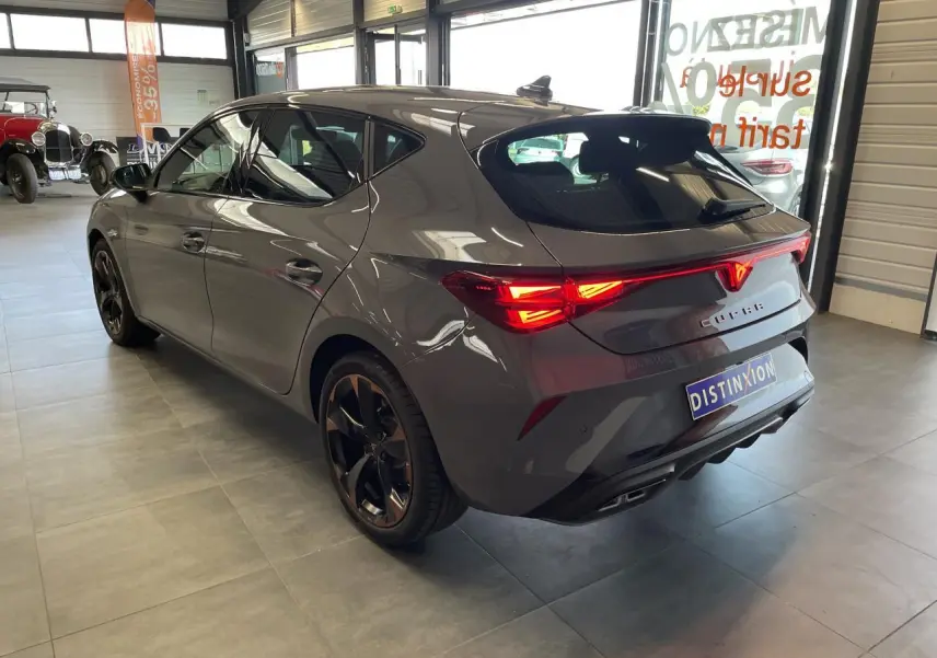 Vue 3/4 arrière droite d'une CUPRA Leon gris magnétique avec feux arrière Tri-LED et jantes alliage 18'' cuivrées.