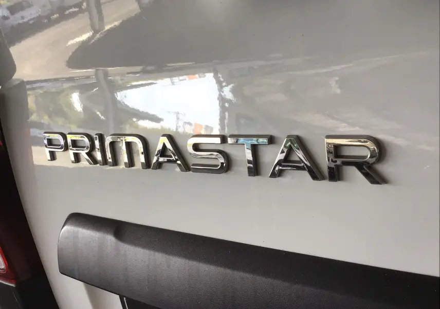 Gros plan sur l'arrière blanc du Nissan Primastar Fourgon avec le logo chromé PRIMASTAR bien visible.