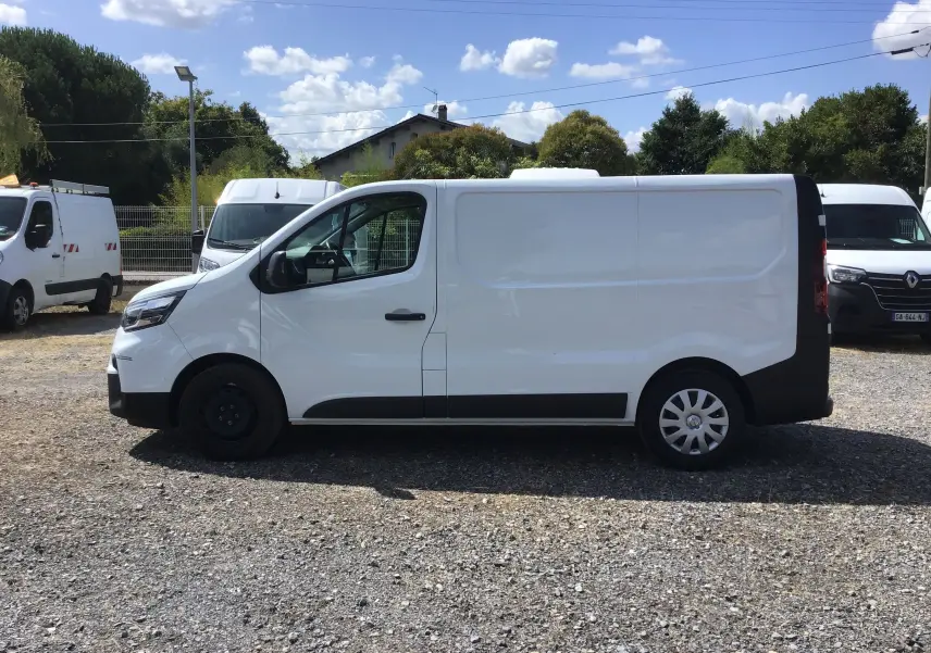Profil latéral droit d'un utilitaire Nissan Primastar blanc avec porte coulissante et jantes différentes avant et arrière.