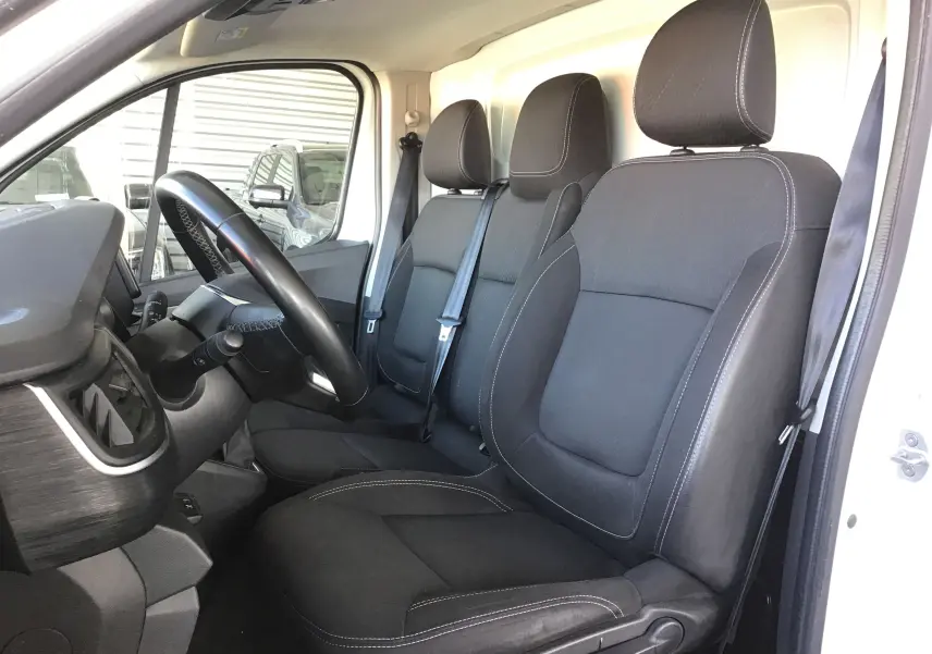 Intérieur du Nissan Primastar blanc 2022 vu côté conducteur, avec sièges noirs et volant en vue latérale.