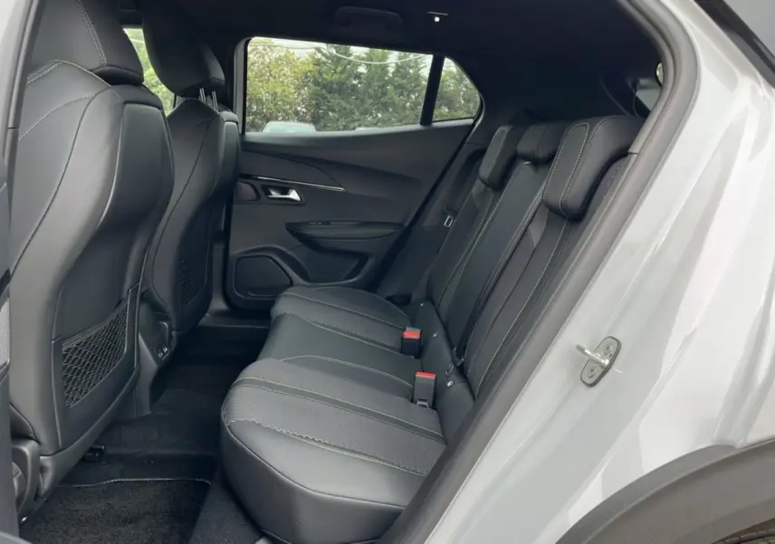 Vue intérieure arrière côté droit du Peugeot 2008 Hybrid 145 GT Vision 2025, sièges noirs avec surpiqûres vertes.