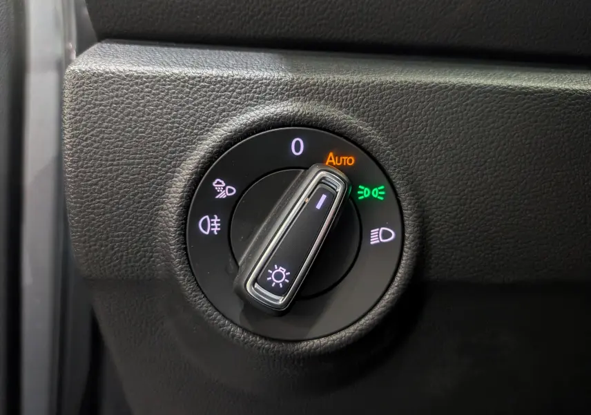 Gros plan sur la molette de réglage des phares du Volkswagen T-Roc gris pyrite, avec indicateurs lumineux activés.