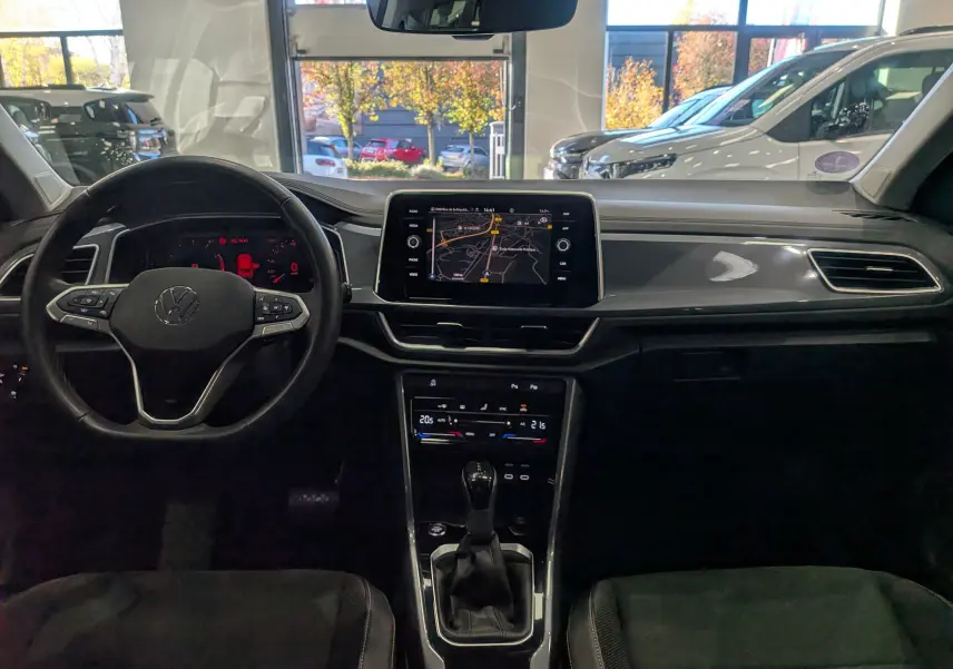 Intérieur du Volkswagen T-Roc 2024 gris pyrite, vue frontale sur le tableau de bord avec écran tactile et volant multifonction.