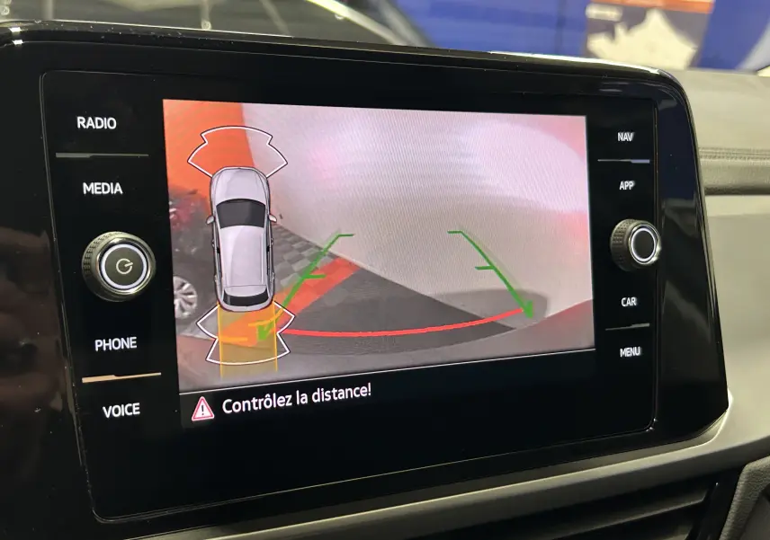 Écran central du Volkswagen T-Roc TSI 150 gris Indium montrant l’assistance au stationnement avec vue caméra arrière.